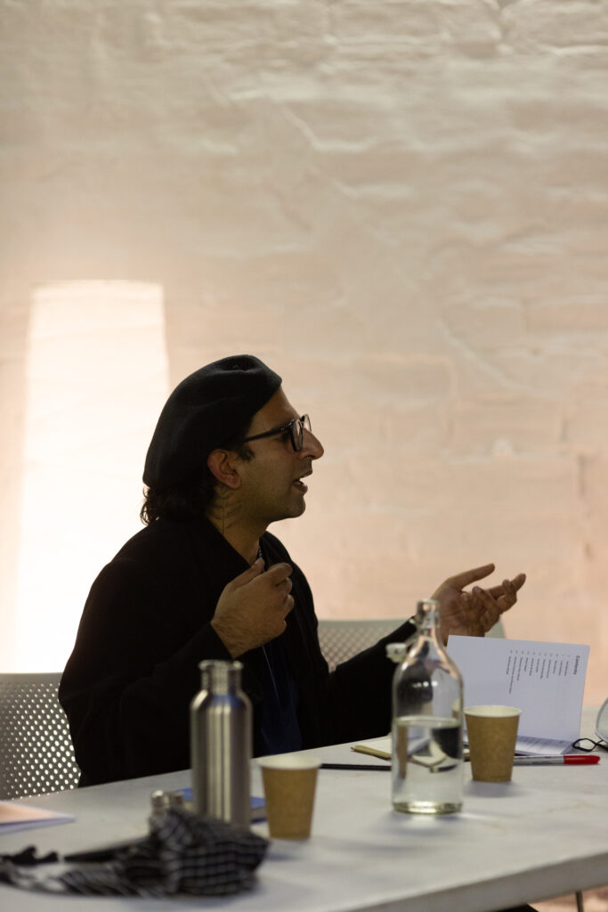 Side profile of Hussein Mitha, they are mid talking, expressively using their hands