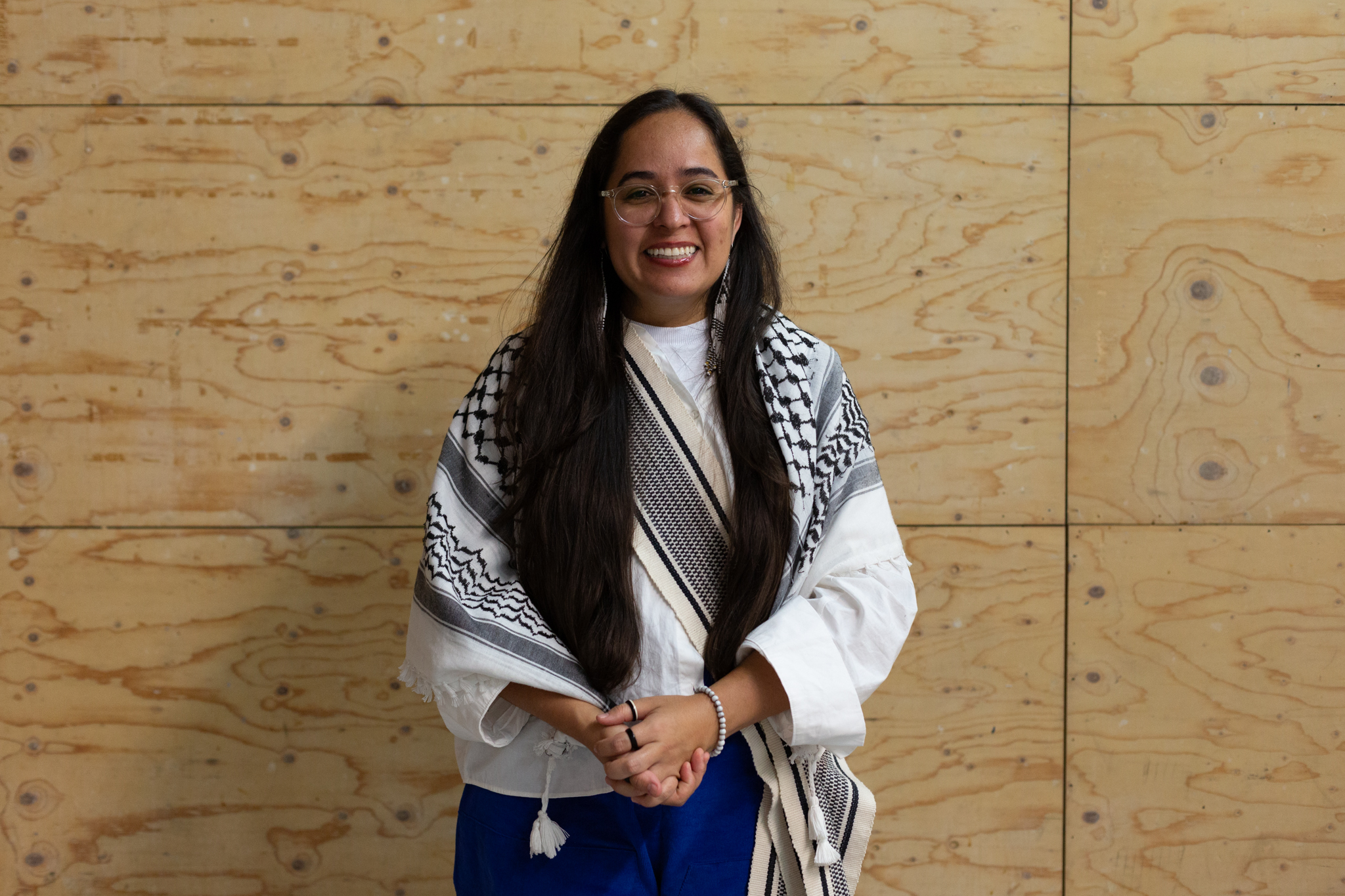 Geni Núñez smiles warmly, they wear glasses and ave long dark hair
