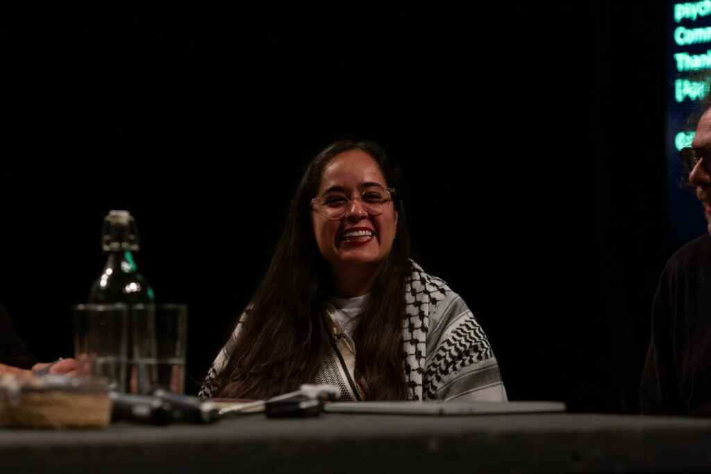 Geni Núñez smiles broadly while in a discussion event with Amilcar Packer