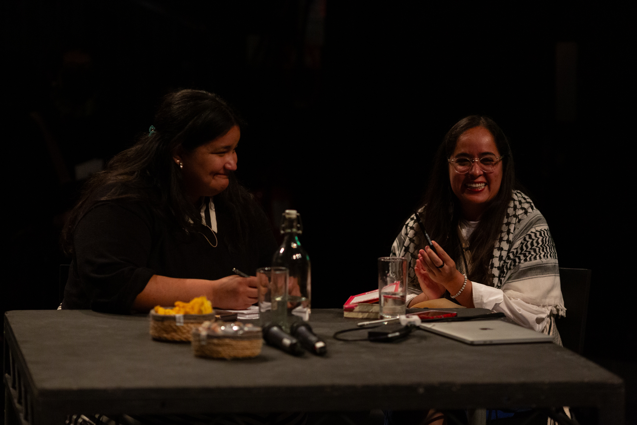 Geni Núñez and the Language Interpreter sit closely smiling and laughing.