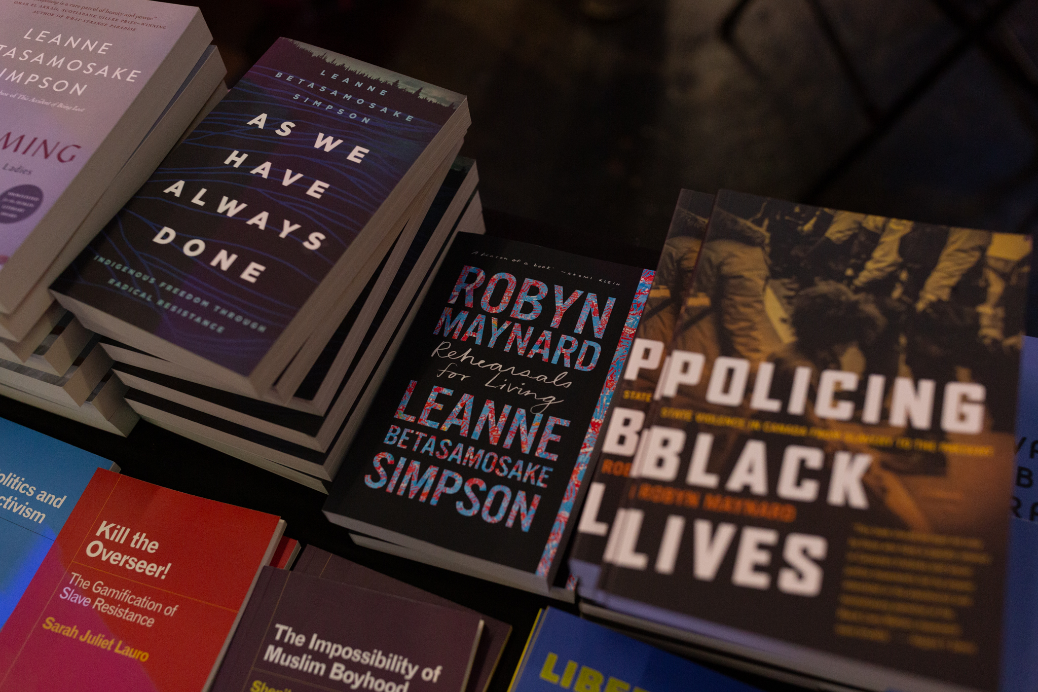 Stacks of books which featuring "Rehearsals for Living" by Leanne Betasamosake Simpson and Robyn Maynard