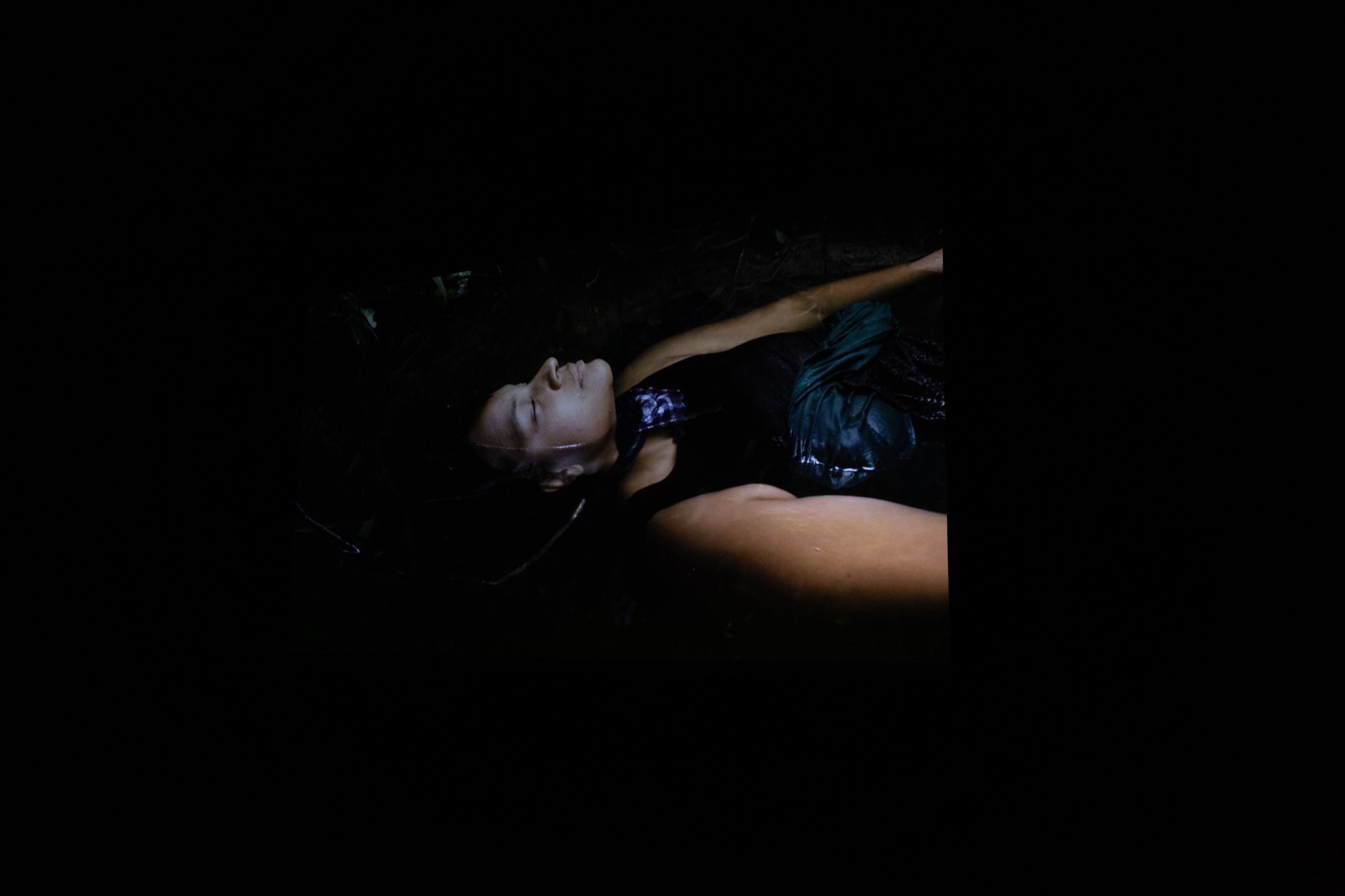 film still from screening of the film Oriana. Someone is floating in water, facing upwards on their back. Their eyes are closed as though relaxing