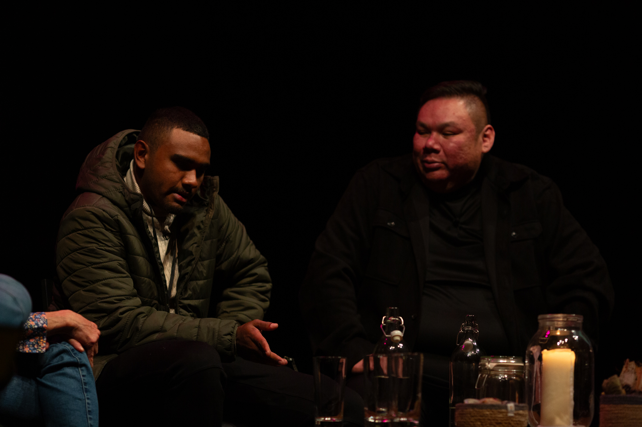 Aiden Sing from Karrabing speaks on stage with Elwood Jimmy. The background is dark and dimly lit.