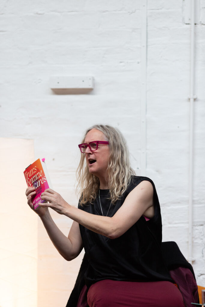 Mijke van der Drift appears to be mid sentence, holding up a copy of Trans Femme Futures.
