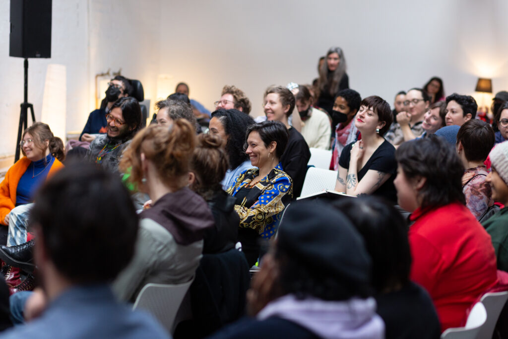 An audience sits smiling and listening intently