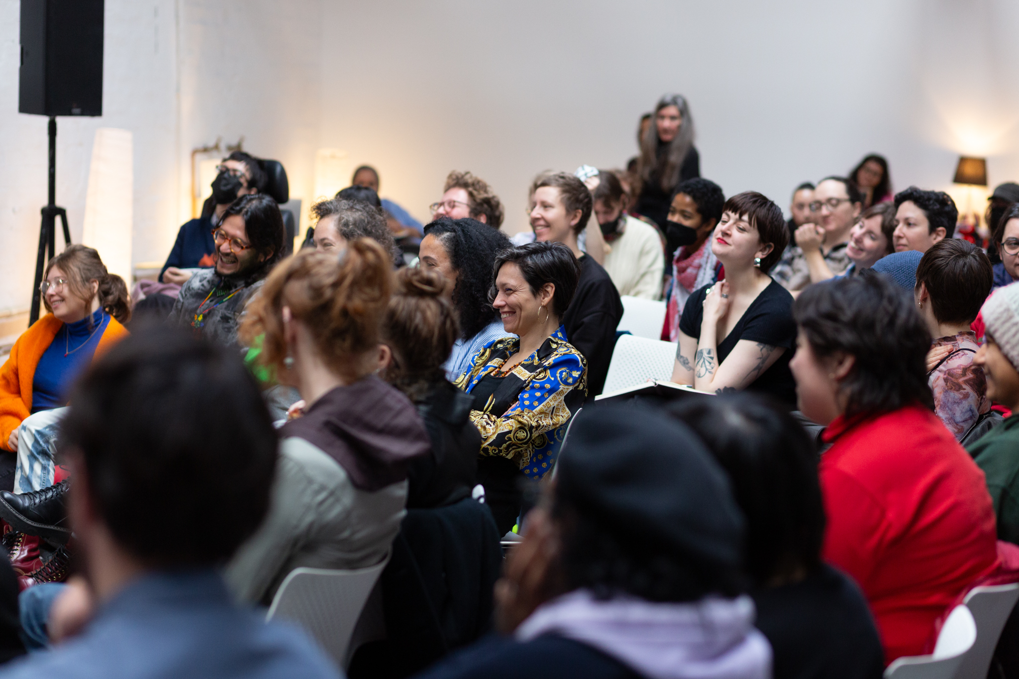 An audience sits smiling and listening intently