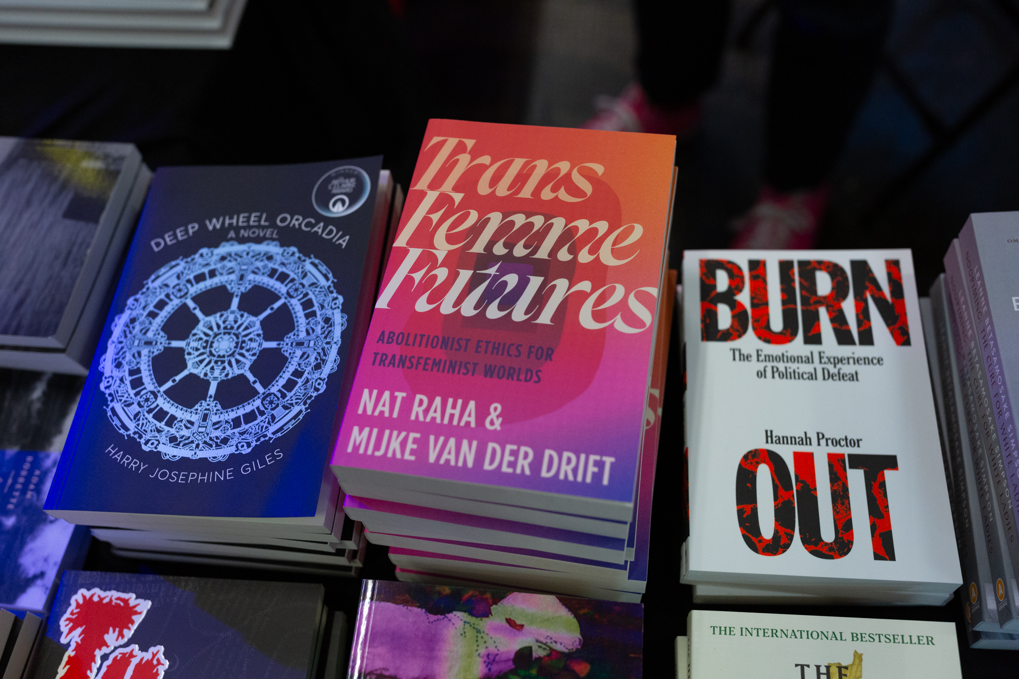 Piles of books stacked featuring "Trans Femme Futures" by Mijke van der Drift and Nat Raha