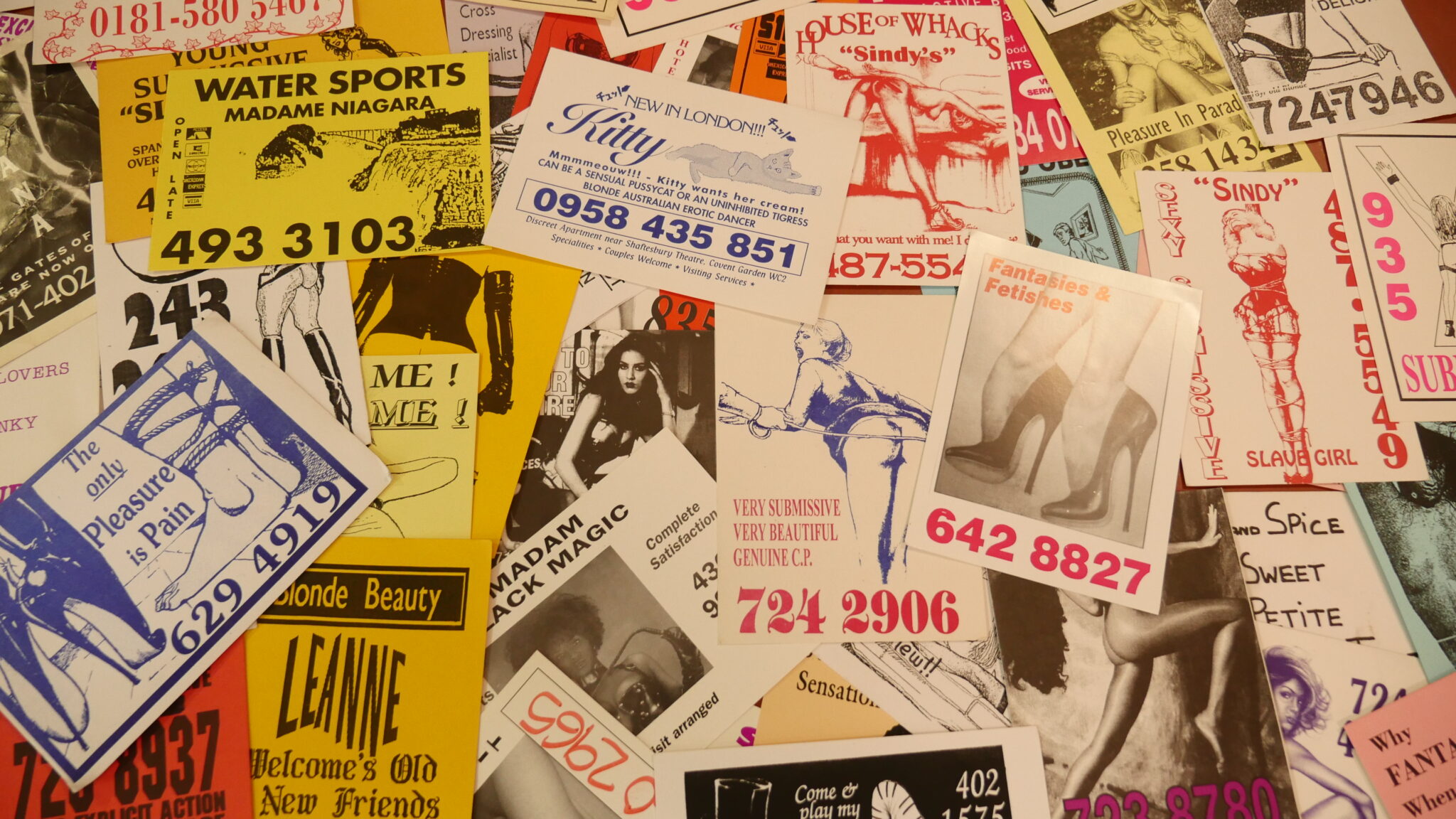 A collection of sex worker call cards scattered over a table.
